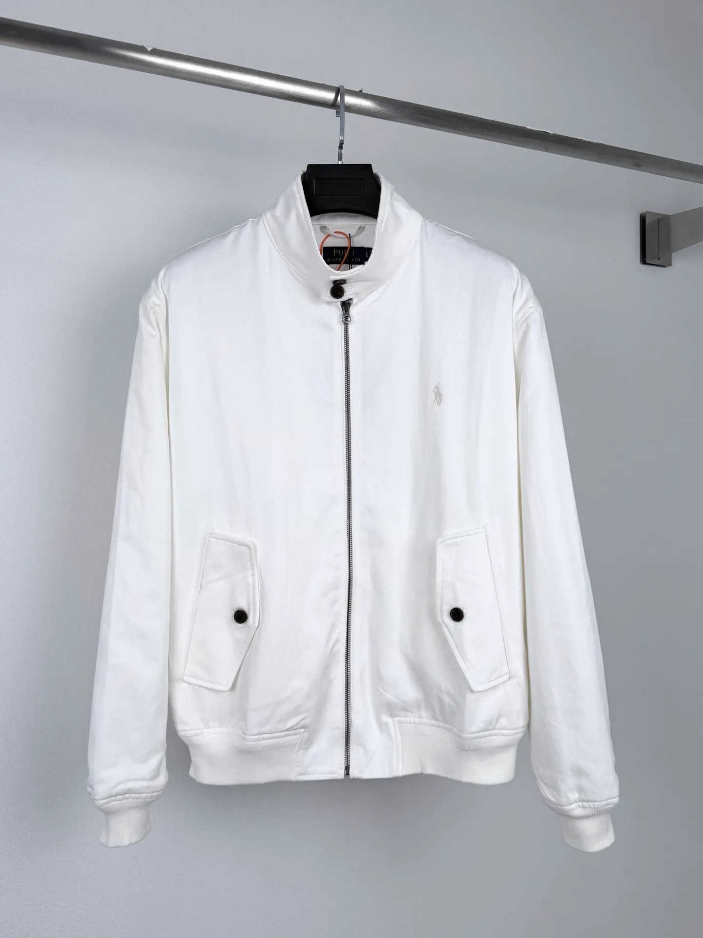 Ralph Lauren embroidered zipper jacket, custom obsidian bamboo honking oblique brocade, crisp and stylish, warm and skin-friendly, radiant milky white spreads over the body, the texture slowly unfolds with the light and shadow, showing unobtrusive classic elegance, exquisite pony embroidery on the left chest, dense and regular stitching, engraved with the brand's handed down totem, concealing the edge, and bringing with it timeless recognition. The neat stand-up collar is embellished with Retro brown buttons. The diagonal pockets are matched with ribs to create a short and relaxed silhouette. Between the plain white body, it embodies the restrained and elegant style of American old money. Process 1: Using imported machine embroidery technology. Using advanced computer control systems and precision mechanical components to achieve the iconic pony embroidery operation. High precision. The lines are smooth and delicate. Process 2: Template machine bag opening. Preset templates guide the position of opening the bag. The accuracy of the shape and size ensures the quality of the bag opening effect. Process 3: The fabrics have been fermented and washed. The hand feel and texture are better. Not easy to deform. Not easy to shrink. Not easy to fade. Maintain long-term beauty. Accessories: Customized 1:1 Ralph Lauren resin buckle. Customized 1:1 Ralph Lauren zipper. Customized 1:1 Genuine Leather lanyard. Customized 1:1 Ralph Lauren trademark. Version: Loose version Size: S M L XL